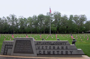 Veterans Cemetery in Estell Manor Park. Memorial visible with American Flags marking grave sites and American flag on flag pole visible.