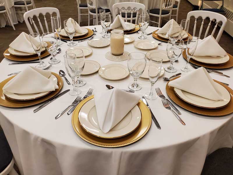g room table set for 8 guest with cream and beige dishes and candle center piece.